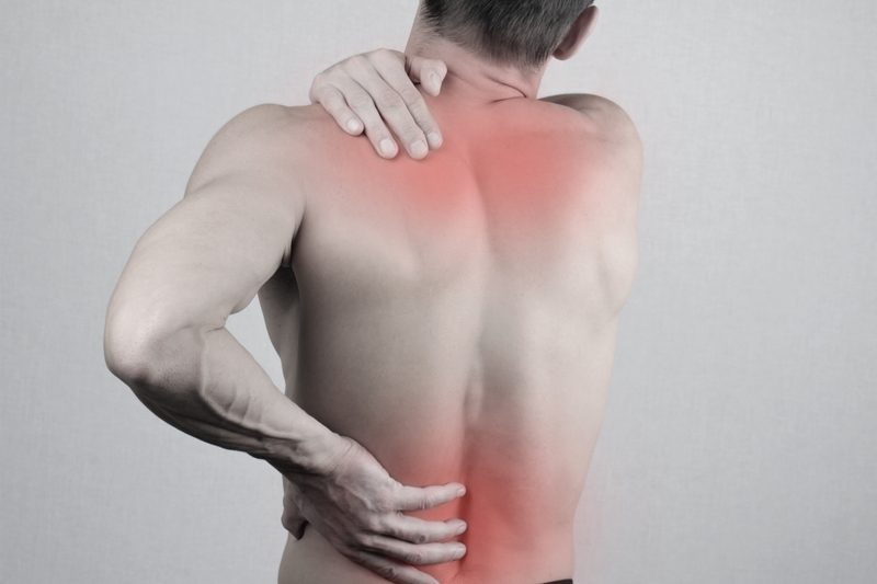 Man with neck and back pain. Man rubbing his painful back close up.