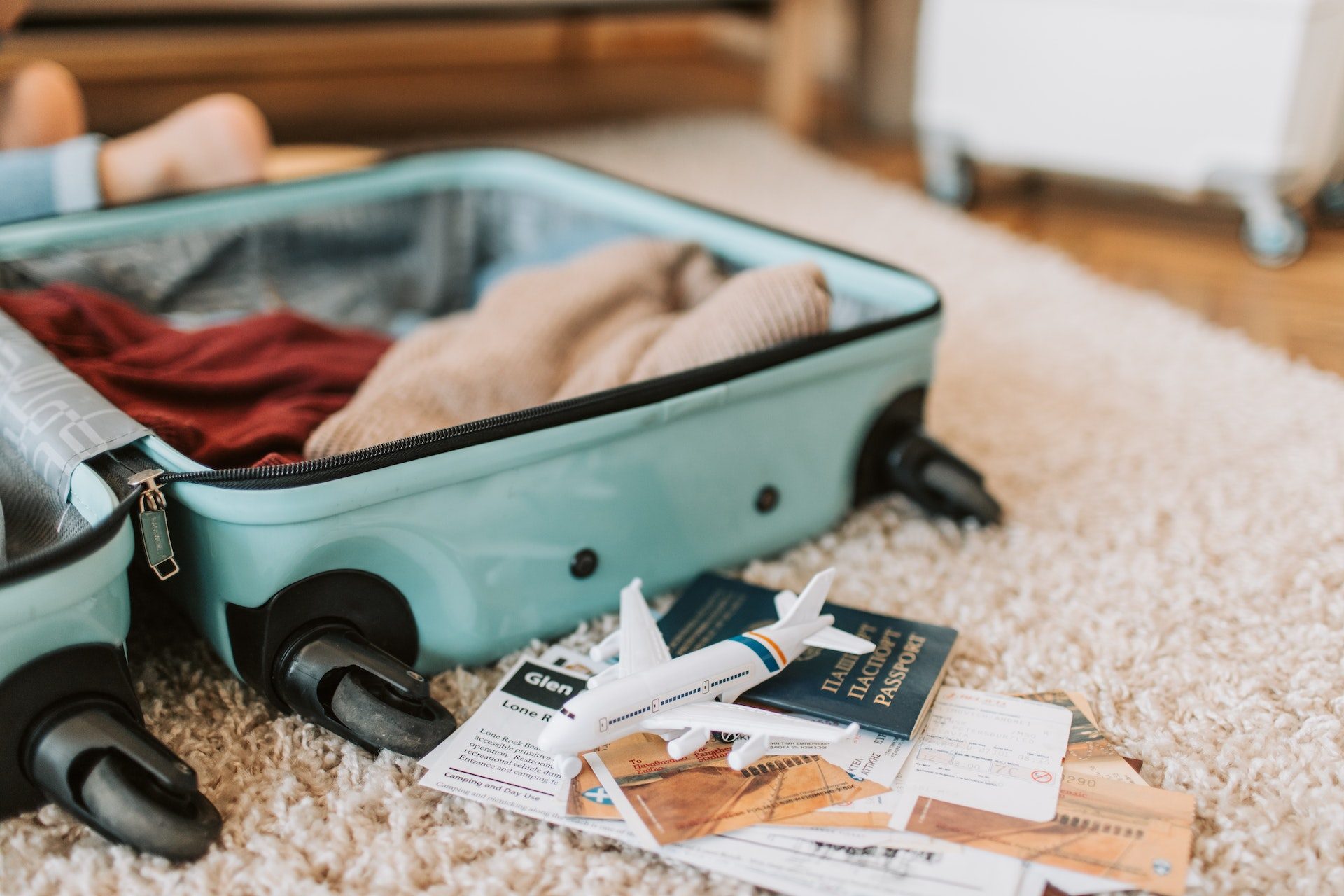 A suitcase open at home being packed with travel documents nearby