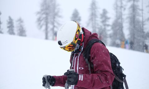 A man standing on the mountain wearing ski gloves.