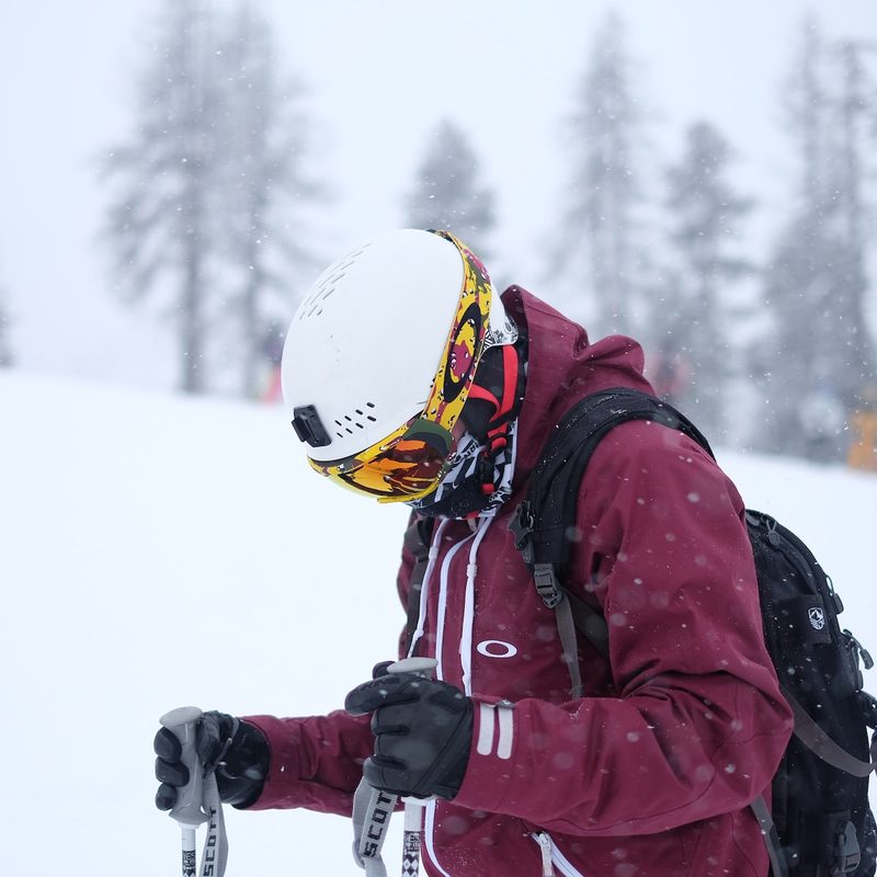 A man standing on the mountain wearing ski gloves.