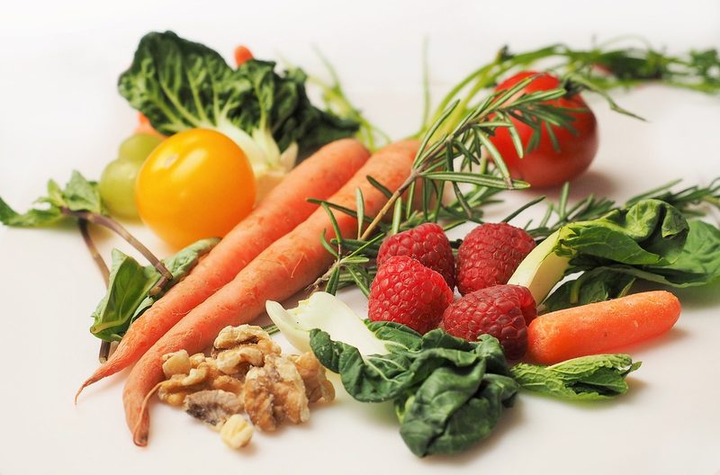 Carrots, raspberries, walnuts, and leafy greens on surface