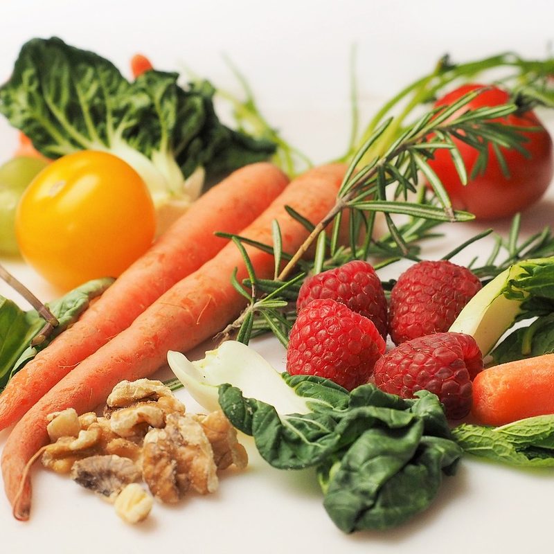 Carrots, raspberries, walnuts, and leafy greens on surface