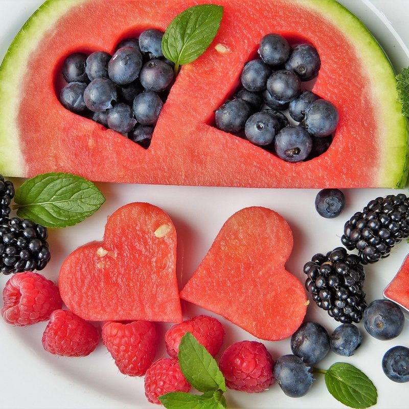 Watermelon and berries arranged on a plate with heart shaped cutouts