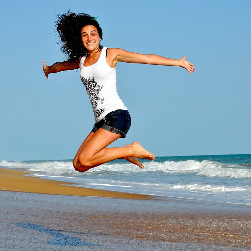Women jumping with arms in the air on the beach
