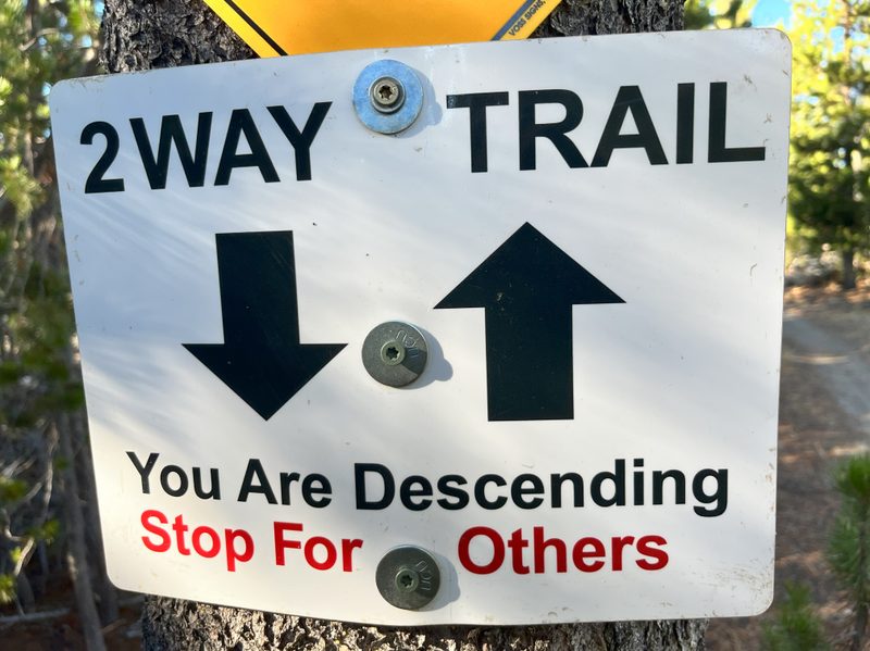 A trail sign indicating riders go up and down the trail