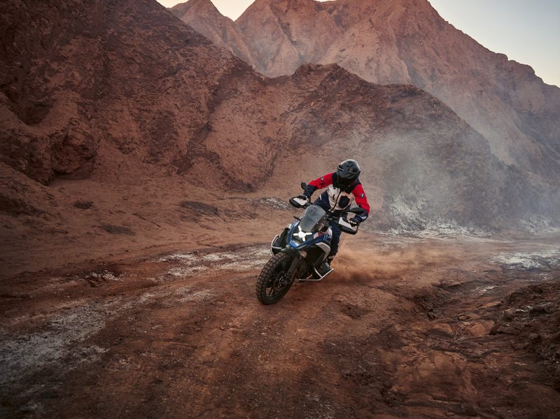 2024 BMW R 1300 GS riding off road on rugged terrain.