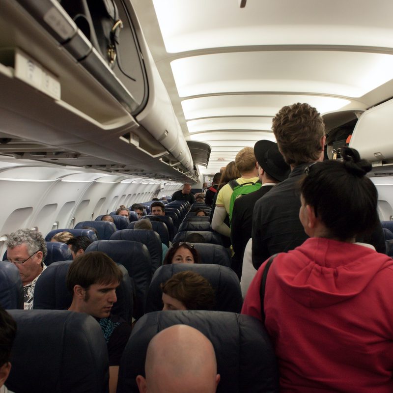 Passengers stand in line waiting to get to their seats.
