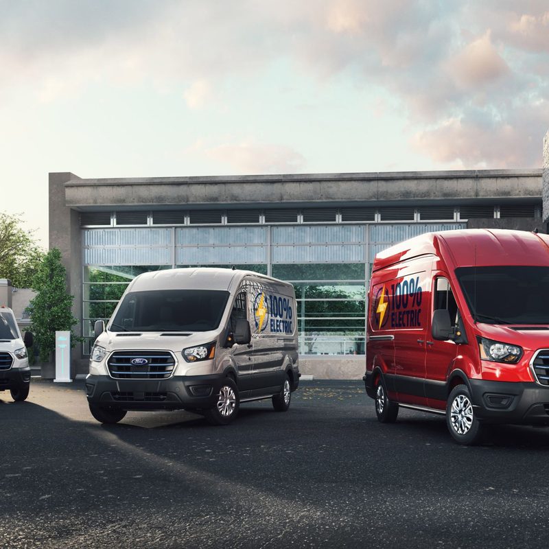 Three Ford E-Transit models parked outside.