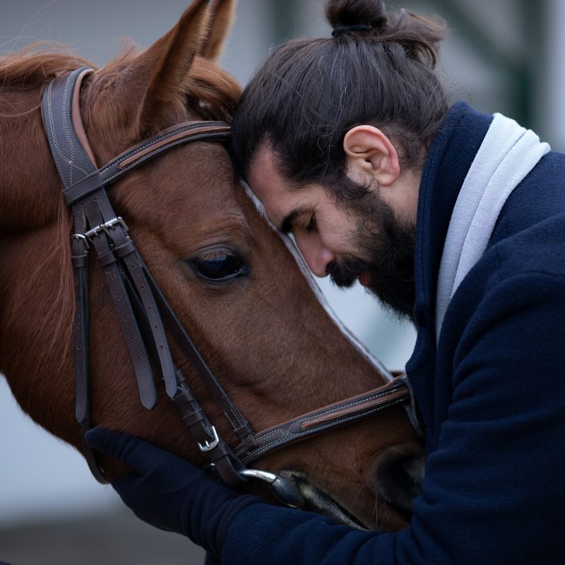 Man hugging a horse in an overcoat