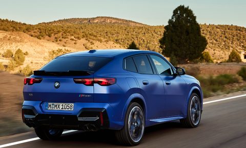 Second generation 2024 BMW X2 compact sports activity coupe right rear three-quarter view driving on a desert highway.