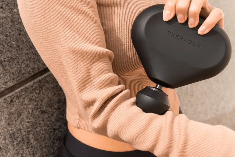 Someone using the Theragun Mini on their chest.
