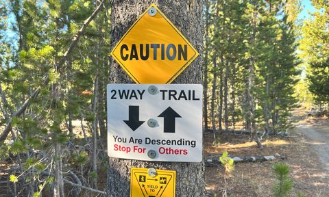 A caution sign on a mountain bike trail telling riders to stop for riders coming up