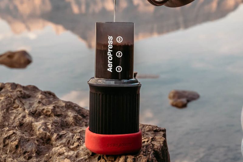A hot water kettle pouring water into an AeroPress Go Portable Camping Coffee Maker.