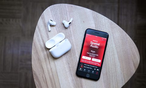 An iPhone with airpods sitting on a table.