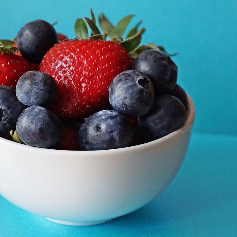 A bowl of berries on blue background