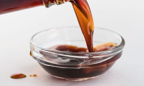 Pouring coconut aminos in clear glass bowl