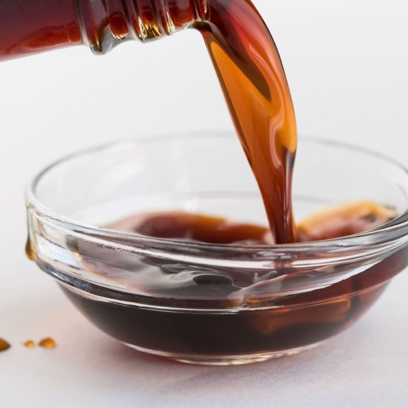 Pouring coconut aminos in clear glass bowl
