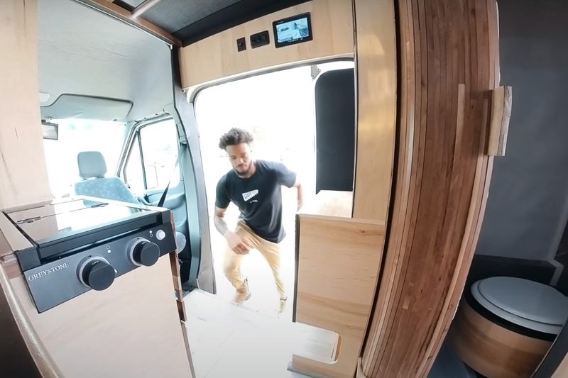 YouTuber DualEx stepping into the kitchen of his custom campervan.