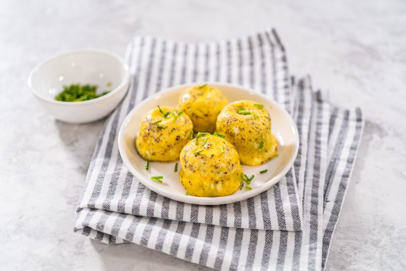 Serving egg bites garnished with fresh chives on a white plate.