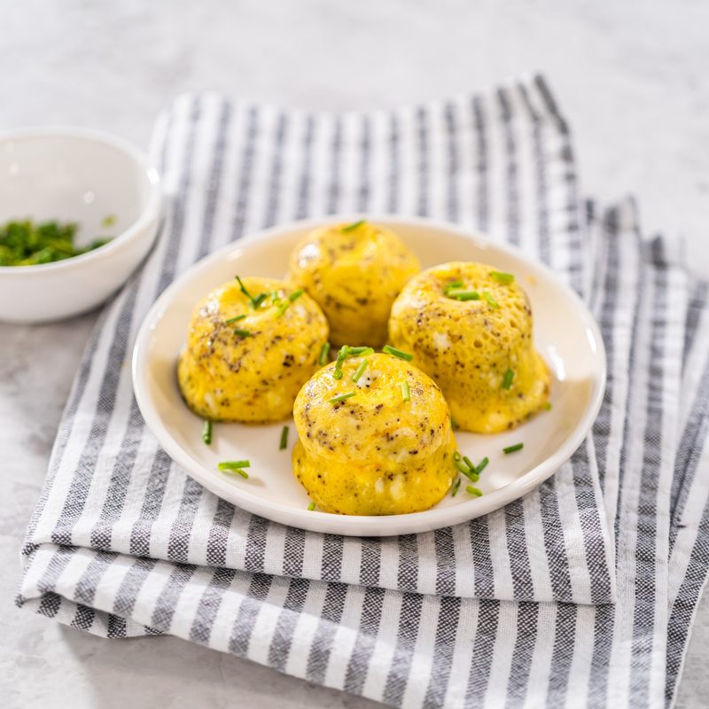 Serving egg bites garnished with fresh chives on a white plate