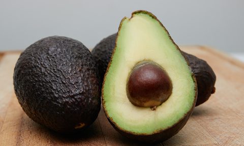 A ripe avocado on a wooden cutting board.