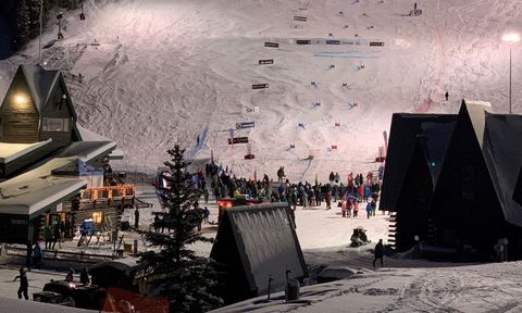 Skiers and snowboarders riding under the alpenglow.