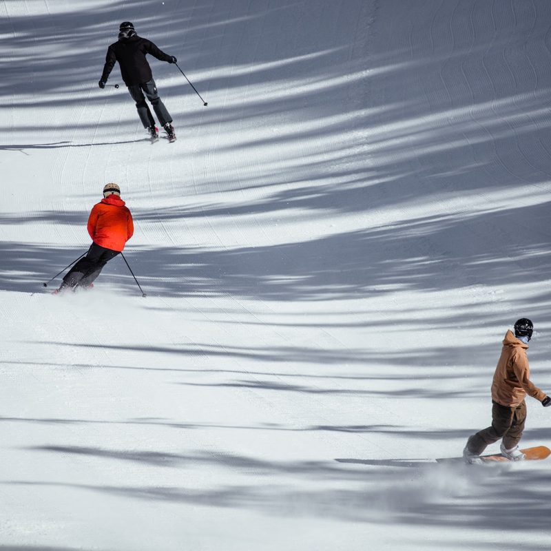 Skiers and snowboarders ride down the mountain