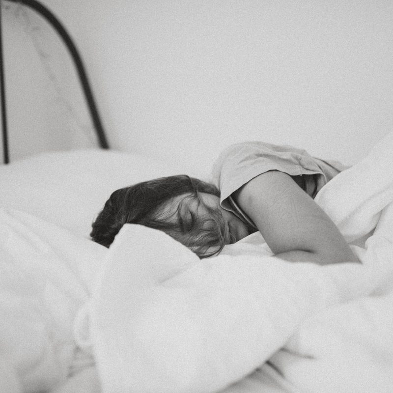 Woman tired laying on bed sleeping black and white