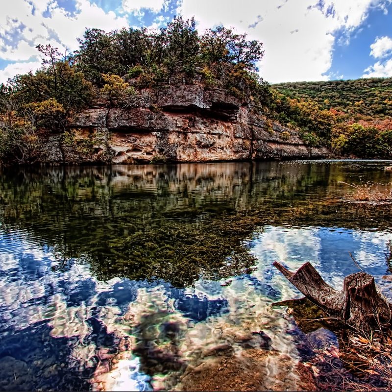 A beautiful view of Lost Maples State Park with Limestone bluffs along a clear river with a vivid reflection