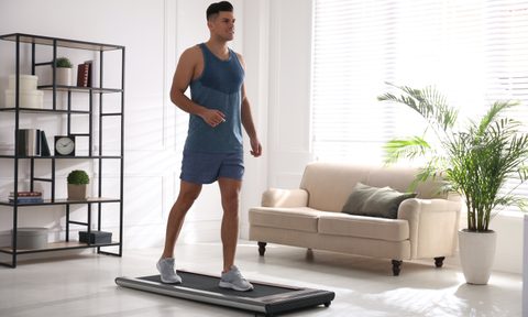 Sporty man training on walking treadmill at home