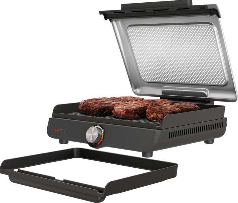 An indoor grill with meat cooking on it.