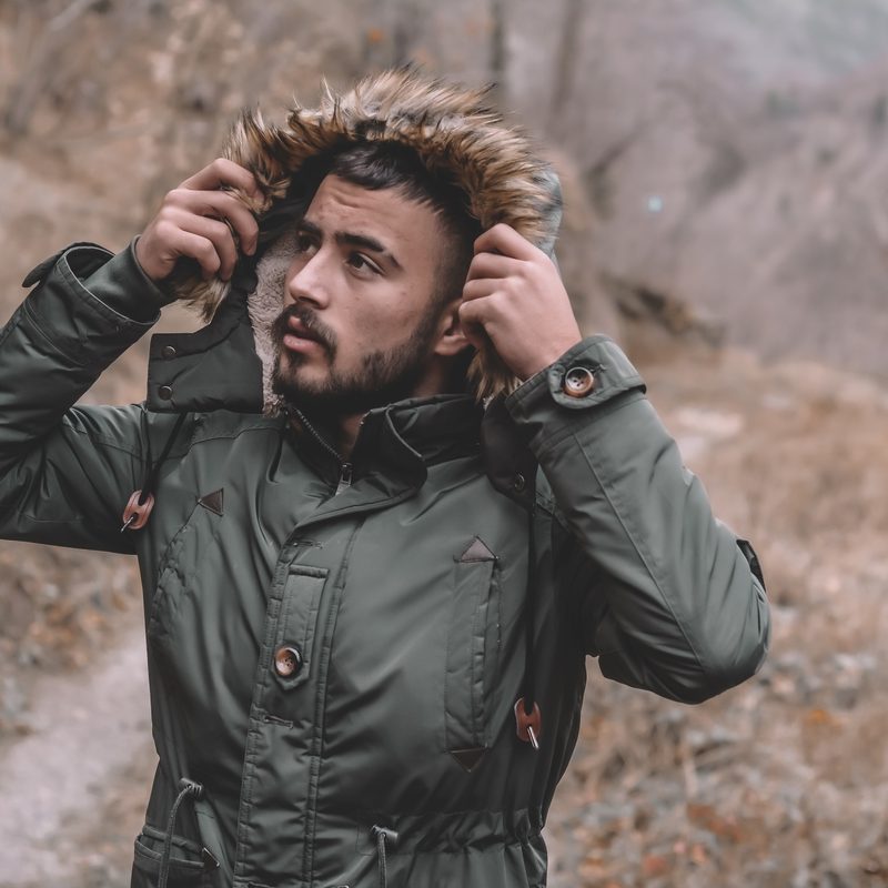 Man in the woods lifting his hood up