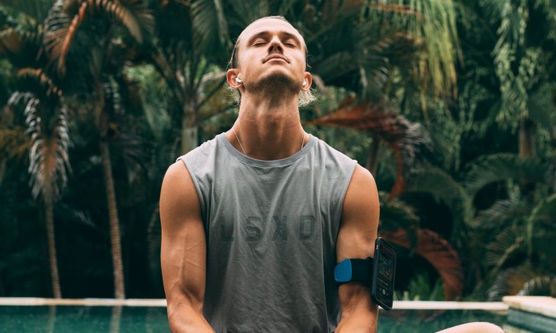 Man doing yoga looking up sitting down in front of trees