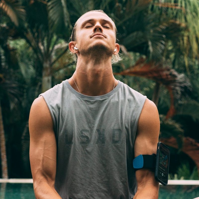 Man doing yoga looking up sitting down in front of trees
