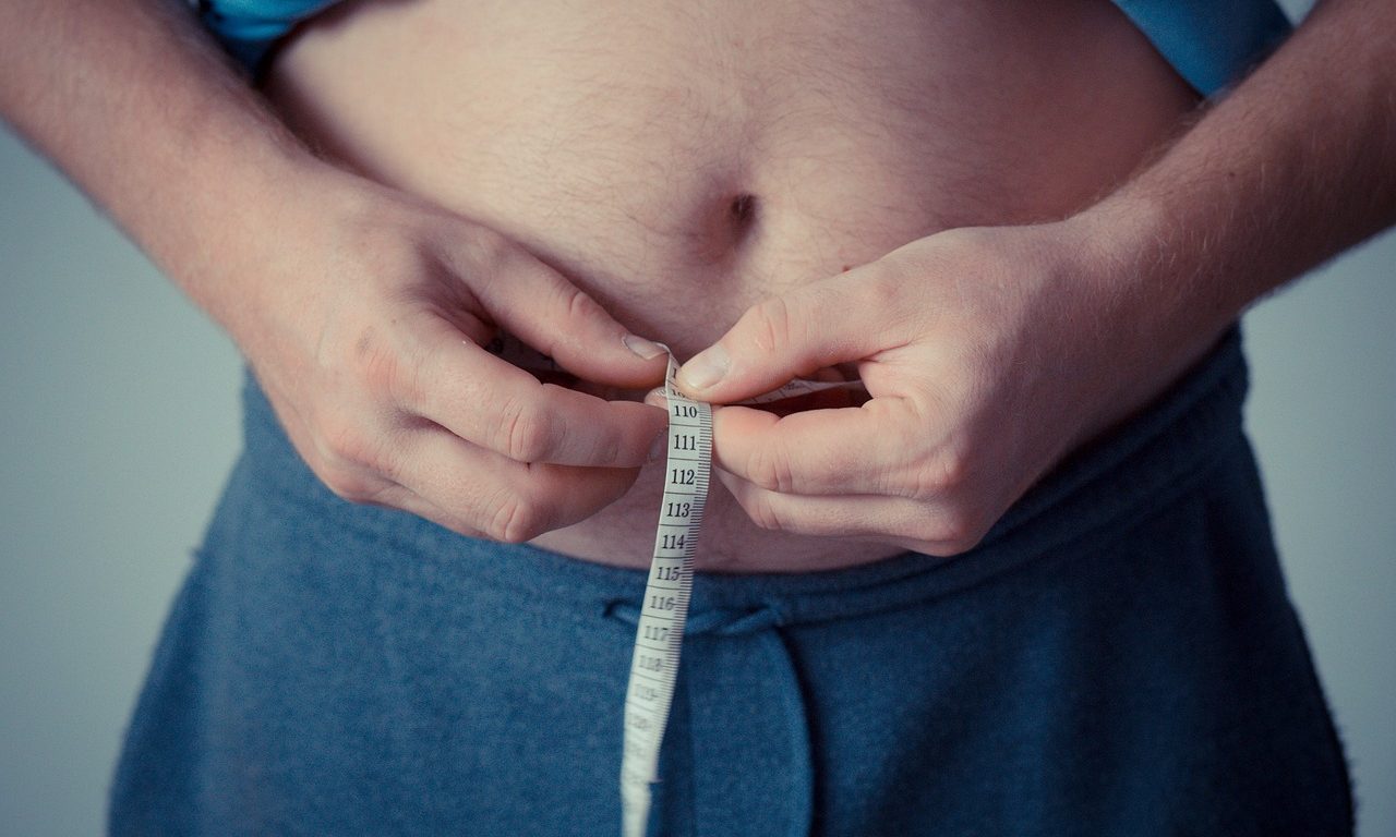 Man measuring his stomach with measuring tape