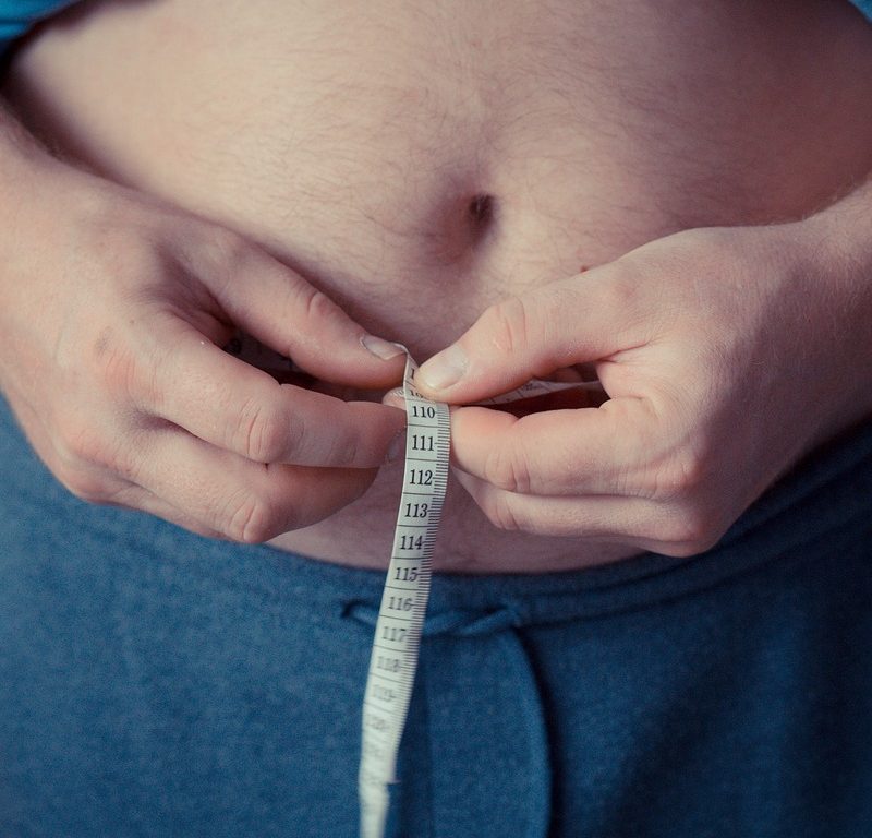 Man measuring his stomach with measuring tape
