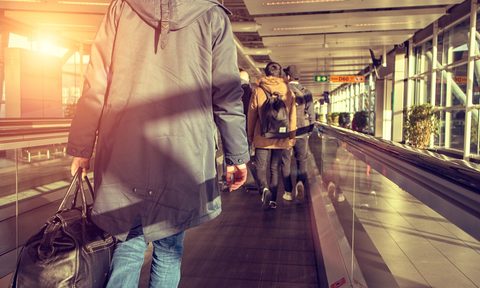 The back of a passenger on a moving sidewalk in an airport
