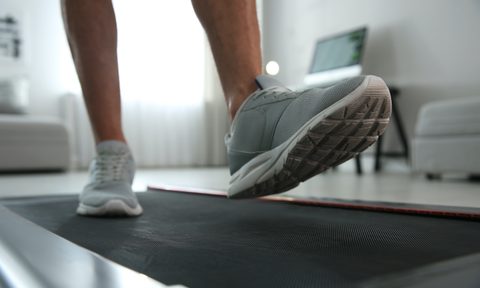 Sporty man training on walking treadmill at home, closeup