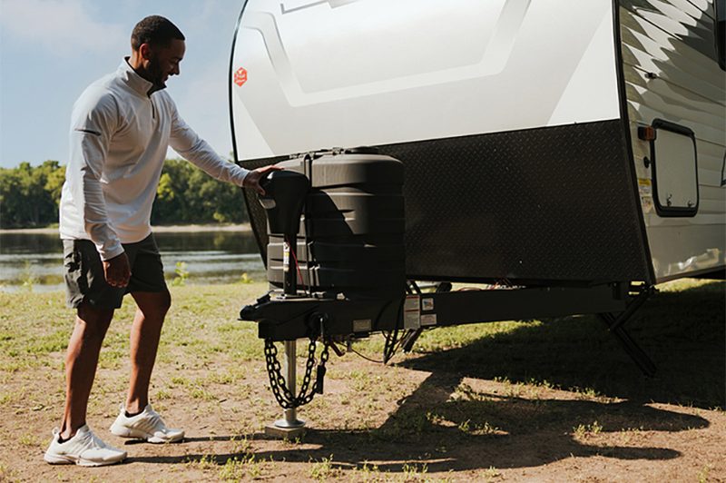 Man operating the electric tongue jack on a Winnebago Access travel trailer.