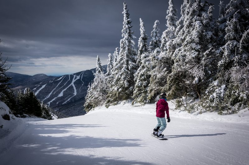 Snowboarder riding down trail at Smuggler's Notch
