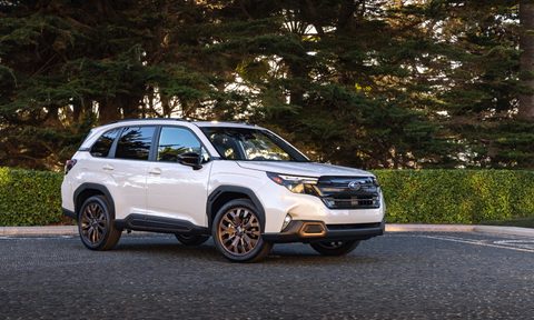 2025 Subaru Forester front right three-quarter view parked on pavement with trees in the background.