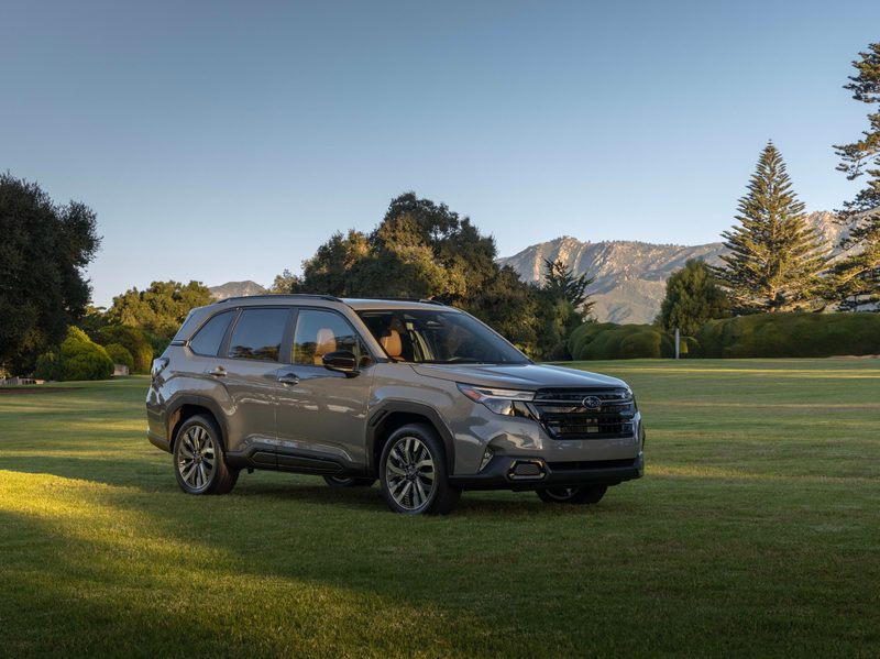 2025 Subaru Forester in light brown color front right three-quarter view parked on lawn with trees in the background
