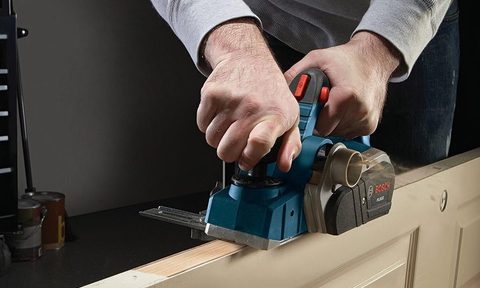 A depiction of a man using a Bosch Woodworking Hand Planer on the side of a door.