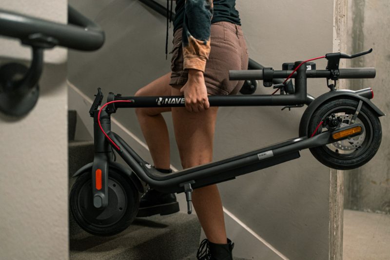 Carrying a NAVEE V40 Pro electric commuter scooter up stairs with the handle folded.