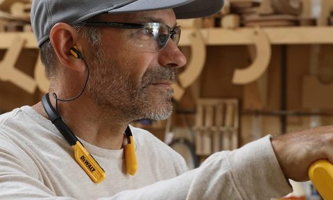 A man wears the DeWalt wireless Bluetooth neckband headphones.