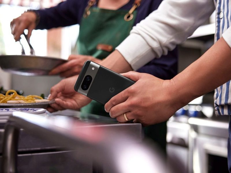 A waiter prepares to deliver food while holding a Google Pixel 8.