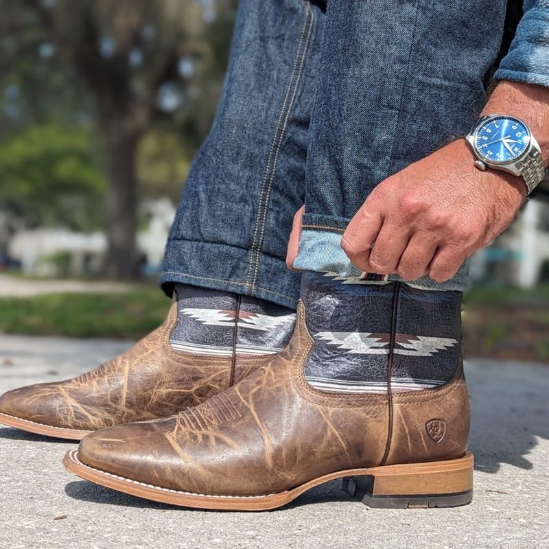 Man rolling jeans up over Ariat boots