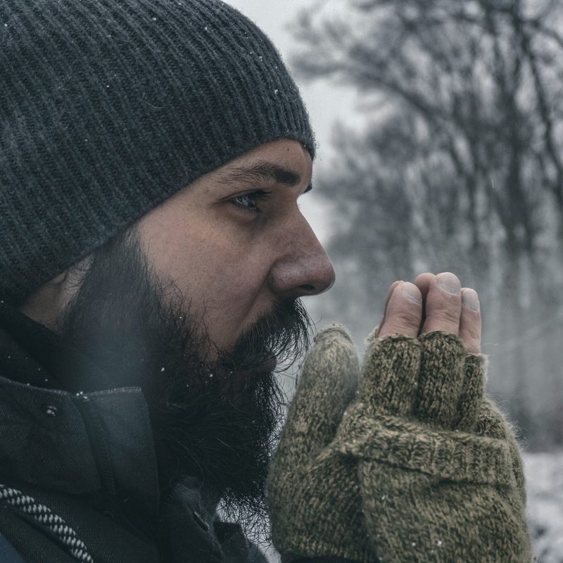 Man in the woods warming his hands