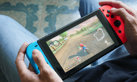 A person plays Mario Kart 8 Deluxe on a Nintendo Switch in handheld mode.