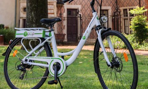 Pi-Pop battery-less electric bike parked on grass in front of a brick building.